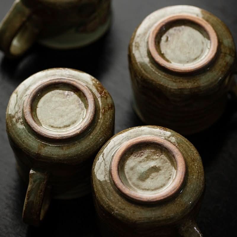 Japan Imported Seto-yaki Flower Cat Mug upside down, showing rustic green ceramic texture.